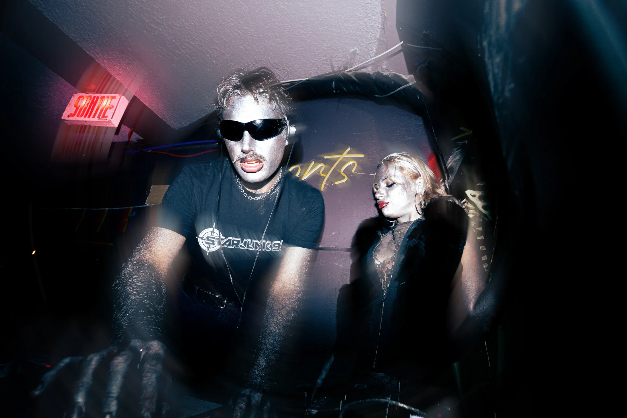 An intimate view of club performance, with vivid lighting, deep shadows, and motion trails.