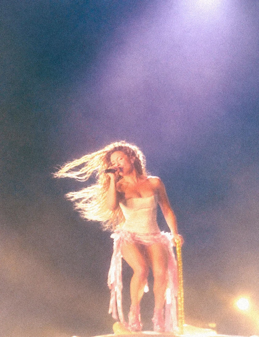 Slayyter performs on a carousel platform with hair caught in golden backlight.
